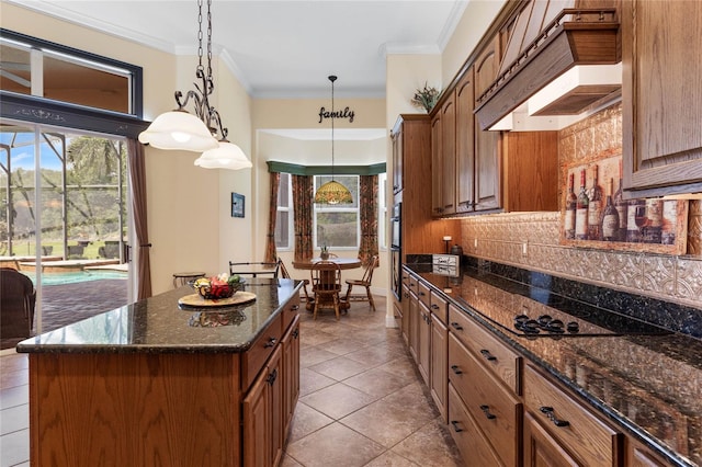 kitchen featuring ornamental molding, a wealth of natural light, a center island, and decorative light fixtures