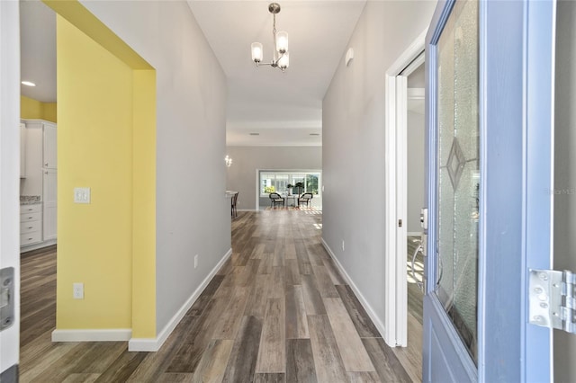 hall with a chandelier and dark hardwood / wood-style flooring