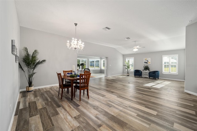 dining area with hardwood / wood-style flooring, a wealth of natural light, and ceiling fan with notable chandelier