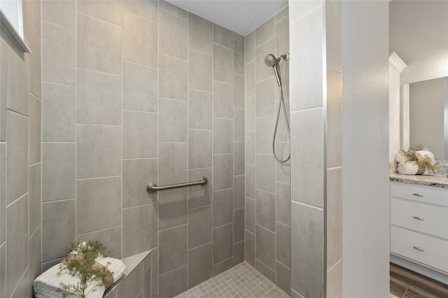 bathroom with vanity, wood-type flooring, and tiled shower