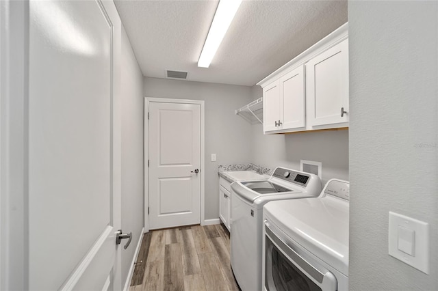 clothes washing area featuring cabinets, a textured ceiling, light hardwood / wood-style flooring, independent washer and dryer, and sink