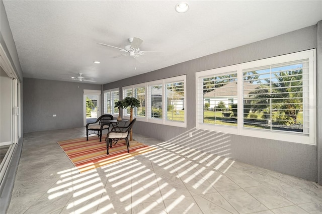 unfurnished sunroom with ceiling fan and a wealth of natural light