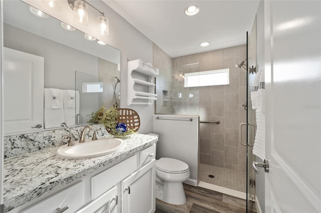 bathroom with vanity, toilet, wood-type flooring, and a shower with door