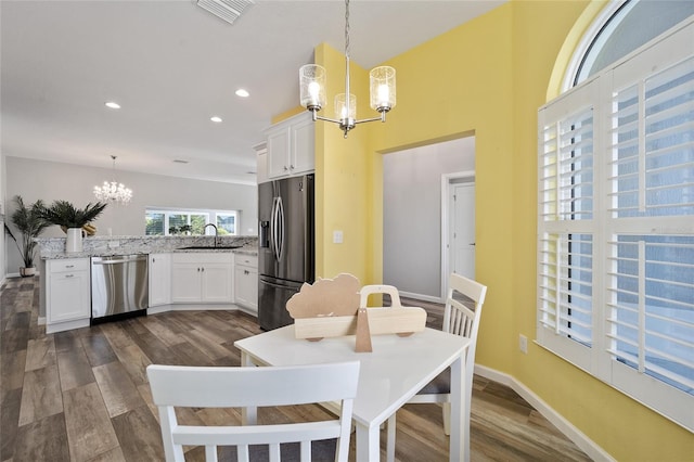 dining area featuring a notable chandelier, sink, and dark hardwood / wood-style flooring