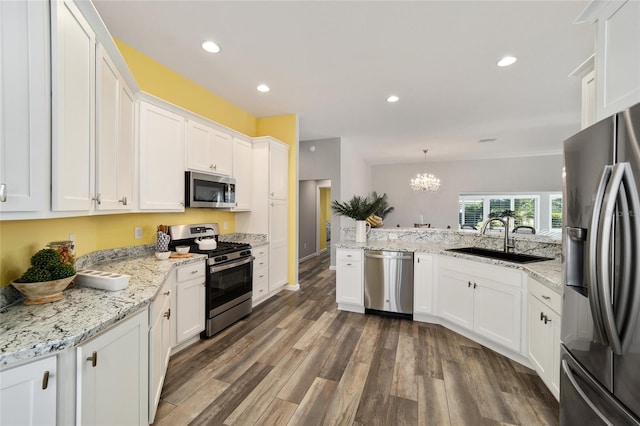 kitchen with white cabinetry, stainless steel appliances, sink, and pendant lighting