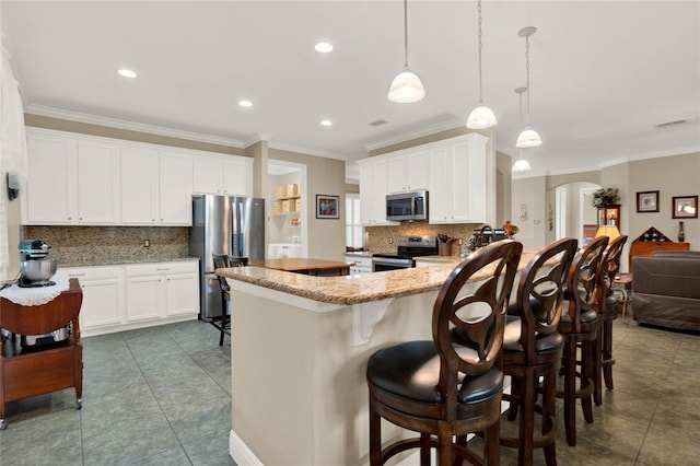 kitchen featuring ornamental molding, white cabinets, appliances with stainless steel finishes, and decorative light fixtures