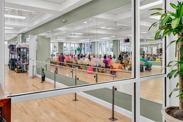 gym with coffered ceiling and hardwood / wood-style floors