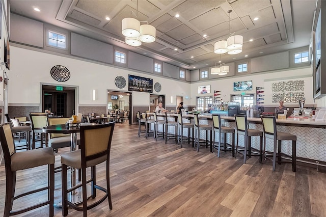 dining area with a towering ceiling, a tray ceiling, coffered ceiling, and hardwood / wood-style flooring