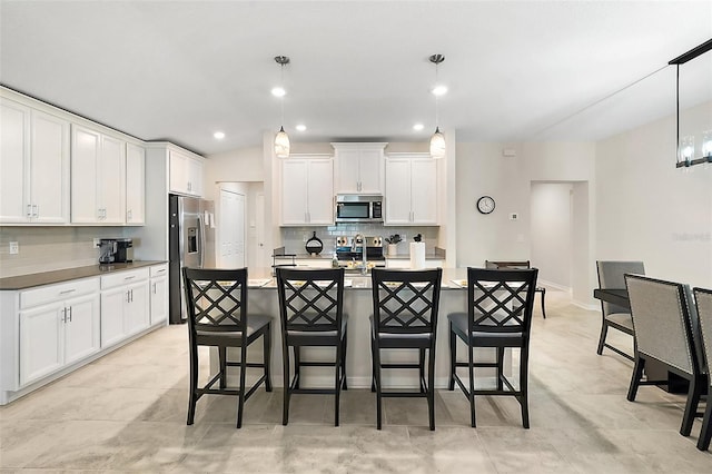 kitchen with pendant lighting, white cabinetry, a breakfast bar, and appliances with stainless steel finishes