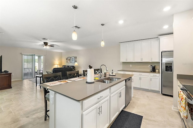 kitchen with appliances with stainless steel finishes, white cabinetry, pendant lighting, a center island with sink, and sink