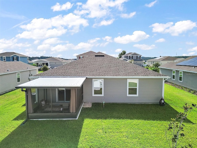 rear view of property with a sunroom, a shingled roof, a residential view, and a lawn