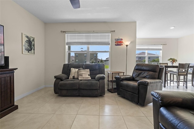 living room with ceiling fan, a textured ceiling, and light tile patterned floors