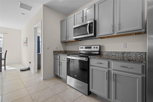 kitchen featuring dark stone countertops, gray cabinets, stainless steel appliances, and light tile patterned flooring