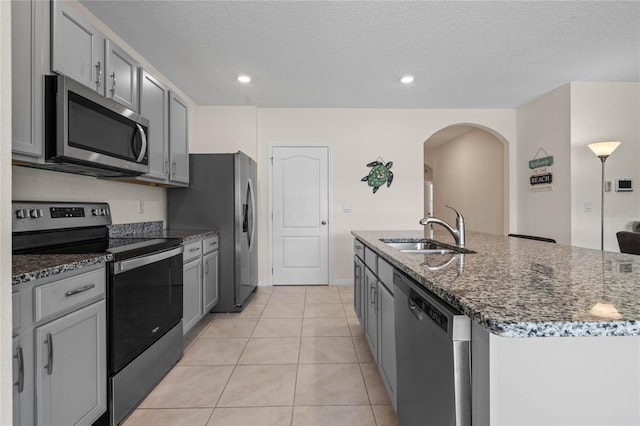 kitchen featuring gray cabinets, sink, stainless steel appliances, a center island with sink, and light tile patterned floors