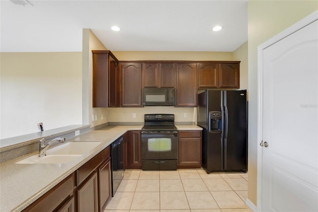 kitchen with light tile patterned floors, sink, dark brown cabinetry, and black appliances