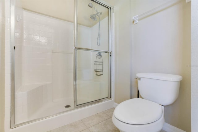 bathroom featuring tile patterned flooring, a shower with shower door, and toilet