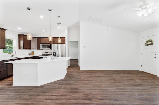 kitchen featuring dark hardwood / wood-style flooring, appliances with stainless steel finishes, a kitchen island, vaulted ceiling, and sink