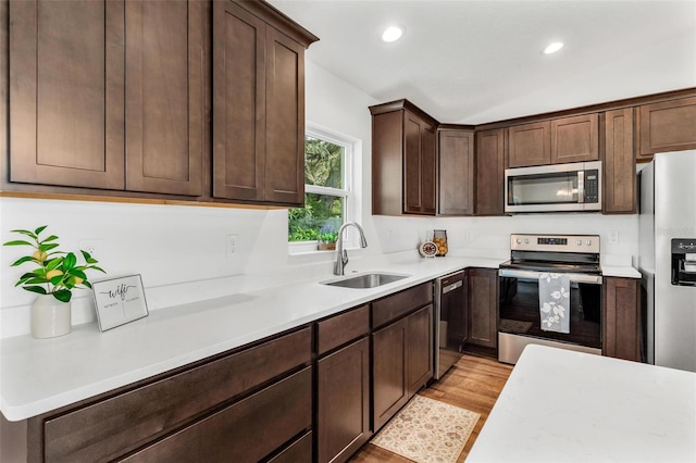 kitchen with light hardwood / wood-style flooring, stainless steel appliances, dark brown cabinets, and sink