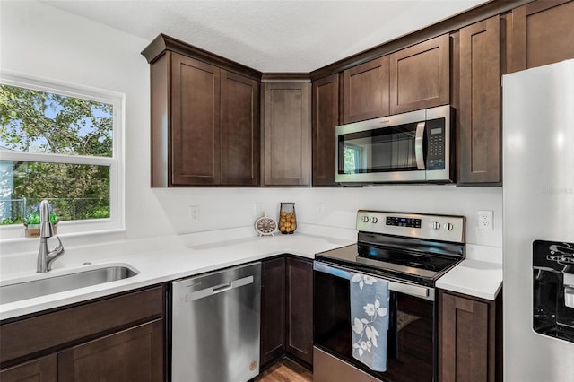 kitchen with dark brown cabinets, stainless steel appliances, and sink