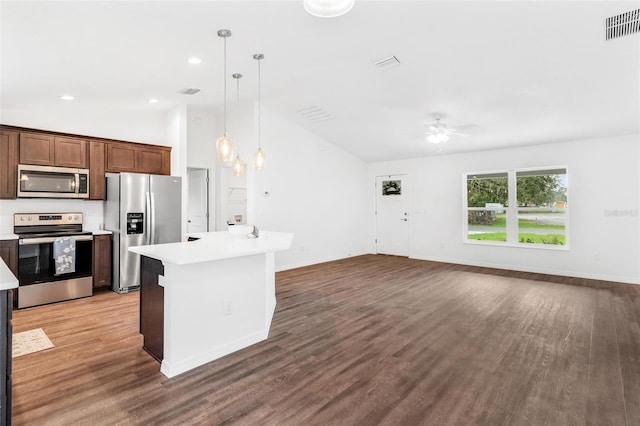 kitchen with vaulted ceiling, appliances with stainless steel finishes, hanging light fixtures, and wood-type flooring