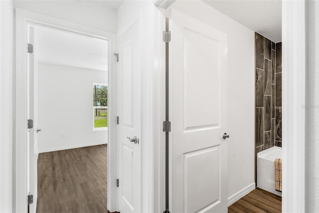 hallway with dark hardwood / wood-style floors and a textured ceiling