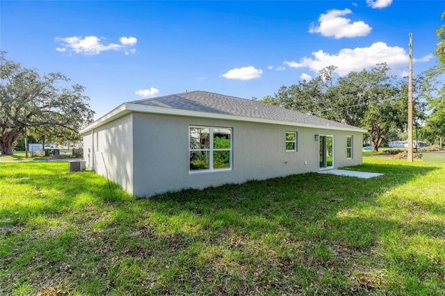 back of property featuring central AC and a lawn