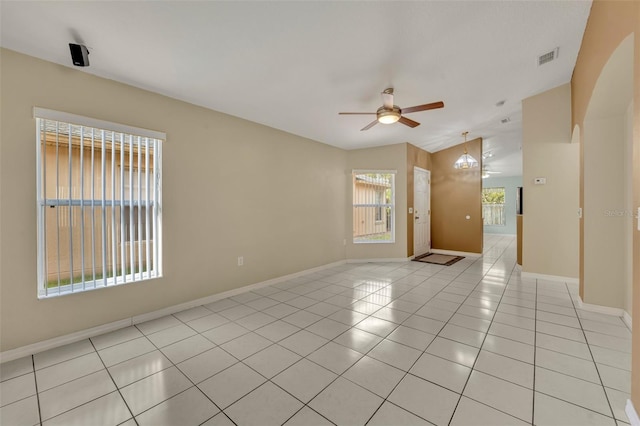 spare room with ceiling fan with notable chandelier, vaulted ceiling, and light tile patterned floors