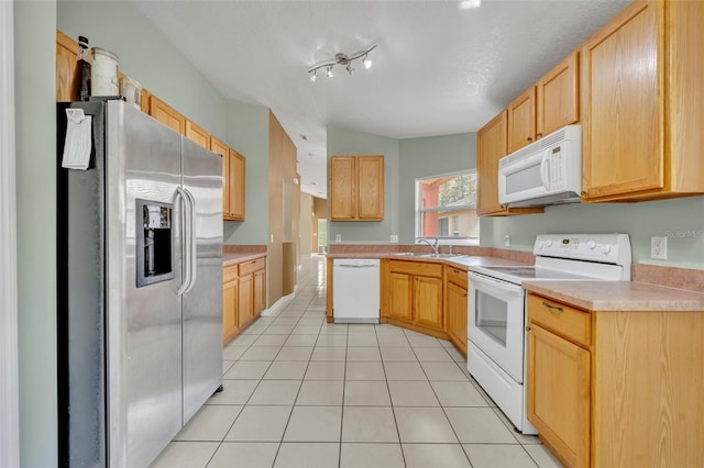 kitchen with light brown cabinets, sink, light tile patterned floors, white appliances, and a textured ceiling