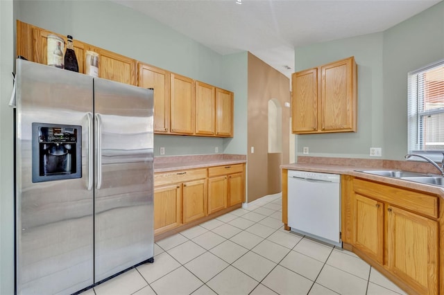 kitchen with stainless steel refrigerator with ice dispenser, light tile patterned floors, light brown cabinets, and dishwasher