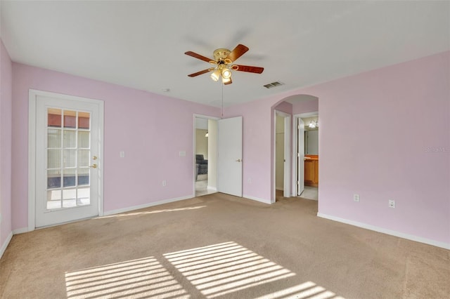 interior space with ensuite bath, ceiling fan, and light colored carpet