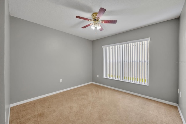 spare room featuring light carpet, ceiling fan, and a textured ceiling