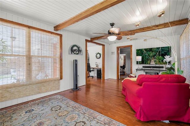 living room featuring wood walls, beamed ceiling, hardwood / wood-style floors, and ceiling fan