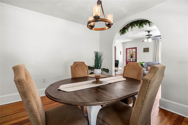 dining room with ceiling fan with notable chandelier, crown molding, and dark hardwood / wood-style floors