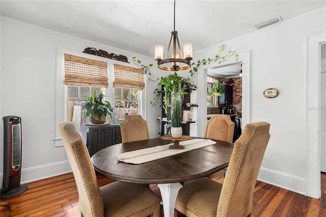 dining space featuring an inviting chandelier, dark hardwood / wood-style floors, and crown molding