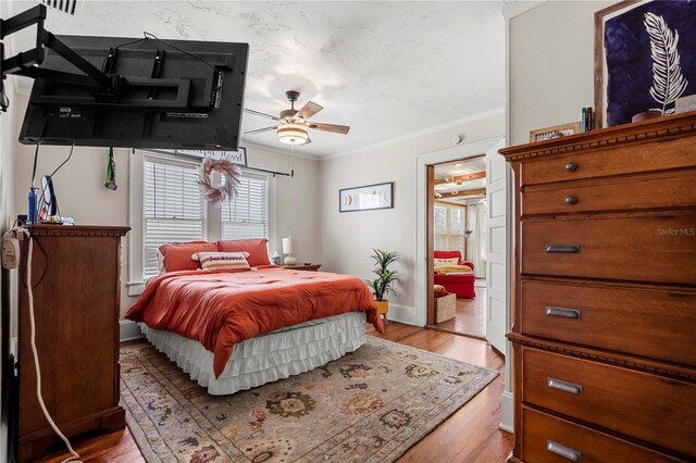 bedroom featuring light hardwood / wood-style floors, ornamental molding, and ceiling fan