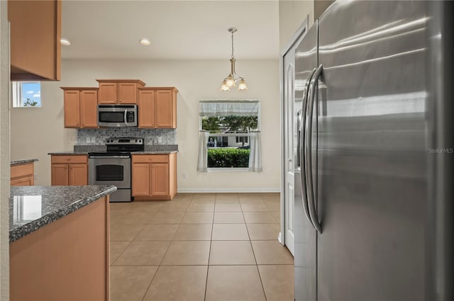 kitchen featuring hanging light fixtures, light tile patterned floors, backsplash, stainless steel appliances, and dark stone counters