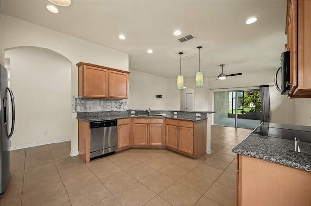 kitchen with sink, kitchen peninsula, hanging light fixtures, appliances with stainless steel finishes, and dark stone countertops