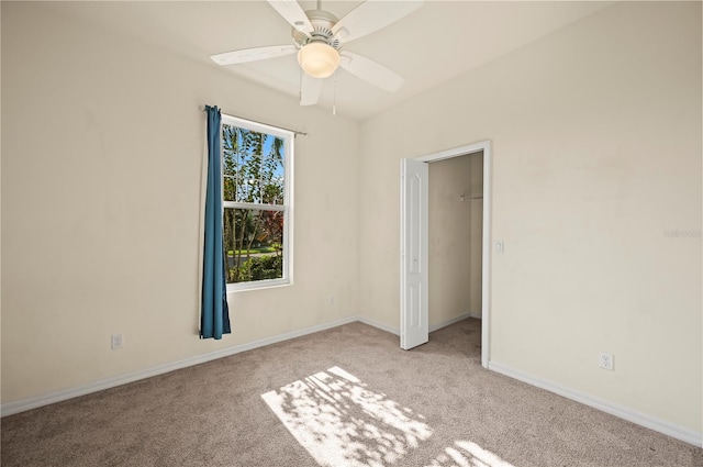 unfurnished bedroom featuring a spacious closet, a closet, ceiling fan, and light colored carpet