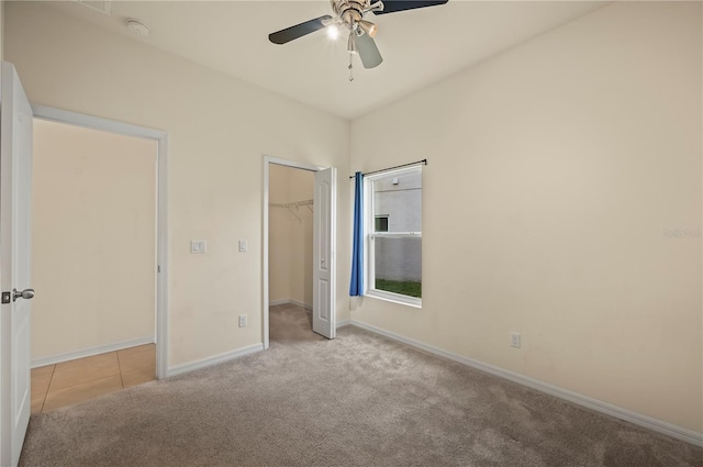 unfurnished bedroom with ceiling fan, a closet, light carpet, and a spacious closet