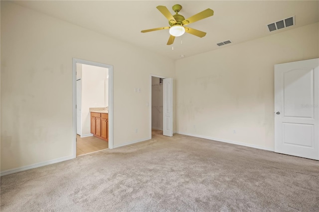 unfurnished bedroom with light carpet, ensuite bathroom, and ceiling fan