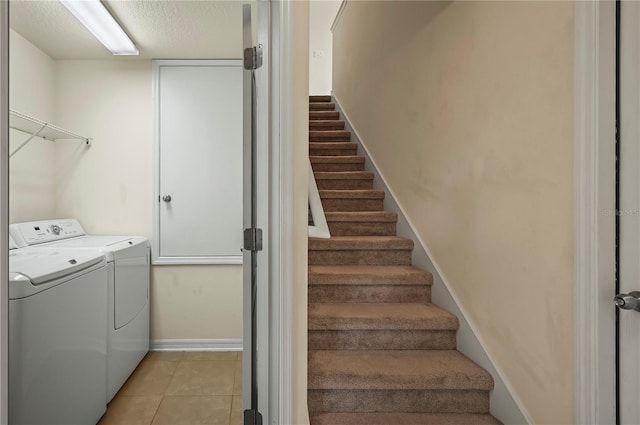 clothes washing area with a textured ceiling, independent washer and dryer, and light tile patterned floors