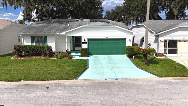 single story home with a shingled roof, a front yard, concrete driveway, and an attached garage