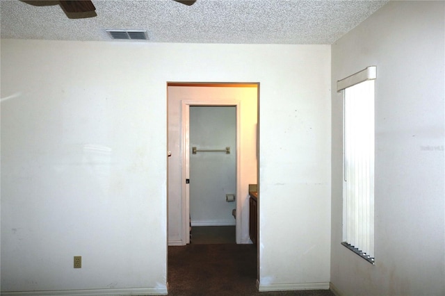 empty room featuring a ceiling fan, visible vents, and a textured ceiling