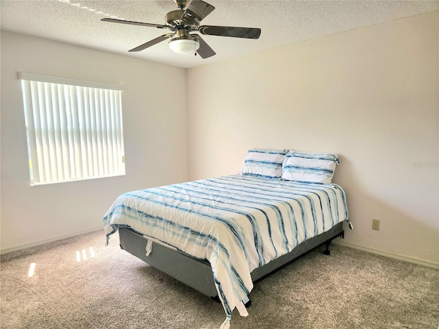 bedroom with a textured ceiling, carpet floors, ceiling fan, and baseboards