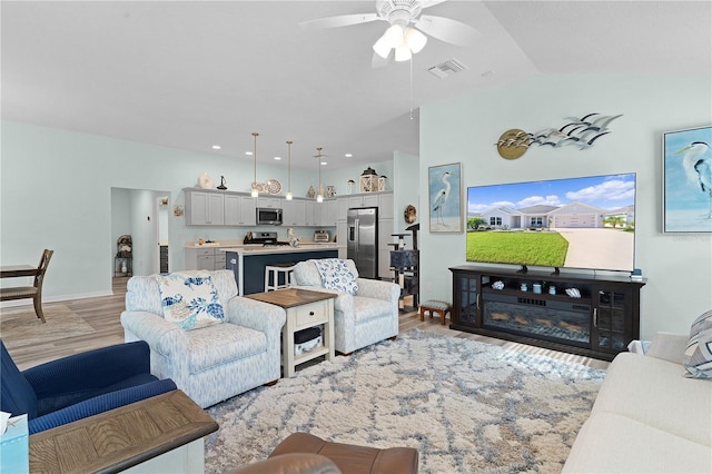 living room featuring light hardwood / wood-style floors, lofted ceiling, and ceiling fan