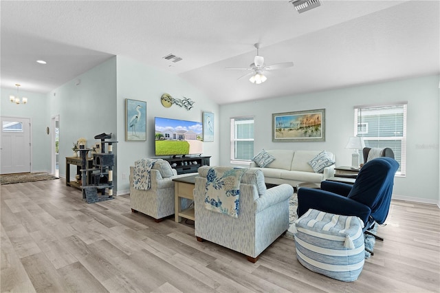 living room with ceiling fan with notable chandelier, light wood-type flooring, lofted ceiling, and a textured ceiling