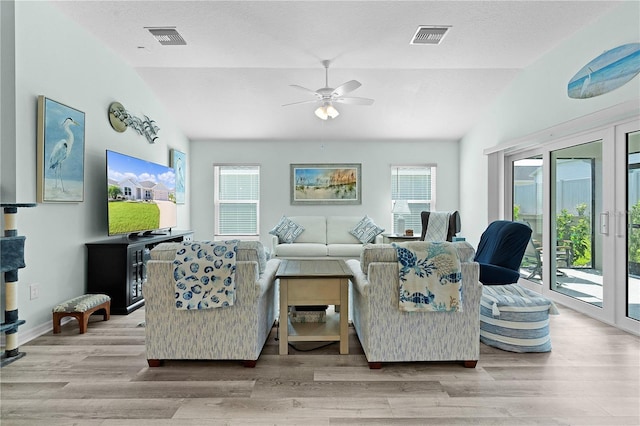 living room featuring ceiling fan, a textured ceiling, light wood-type flooring, and vaulted ceiling