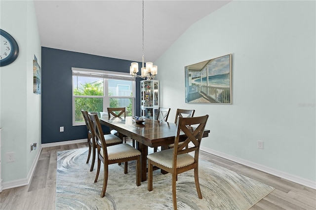 dining space with light hardwood / wood-style flooring, vaulted ceiling, and a notable chandelier