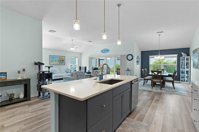 kitchen featuring an island with sink, hanging light fixtures, sink, dishwasher, and vaulted ceiling