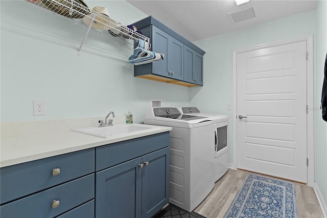 clothes washing area featuring cabinets, a textured ceiling, sink, light hardwood / wood-style flooring, and independent washer and dryer